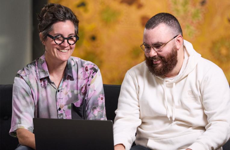 Student and researcher looking at a laptop together.
