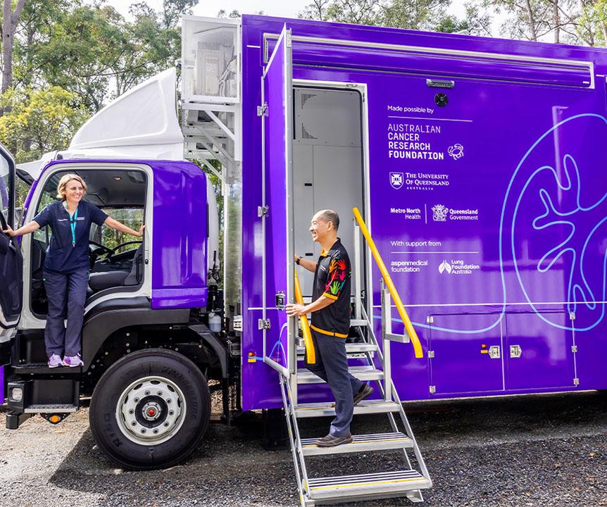 2 people stepping out of a bright purple lung cancer detection truck