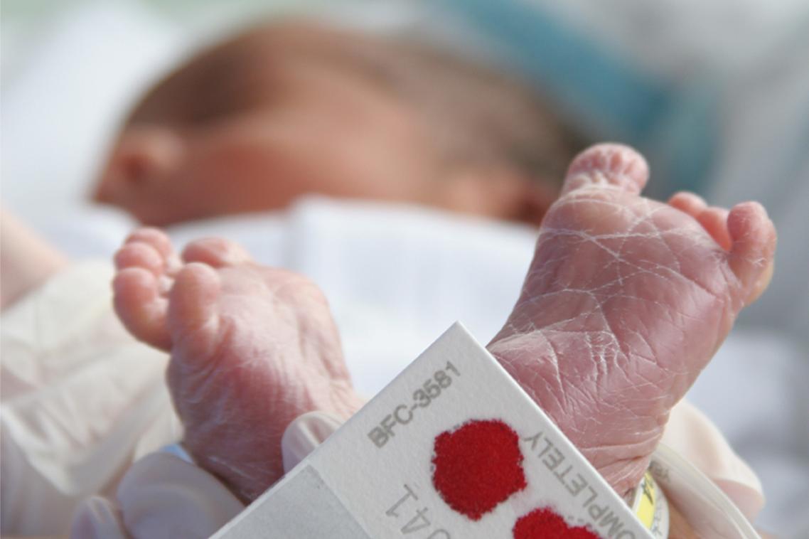 Newborn baby with bloodspot screening test on heel.