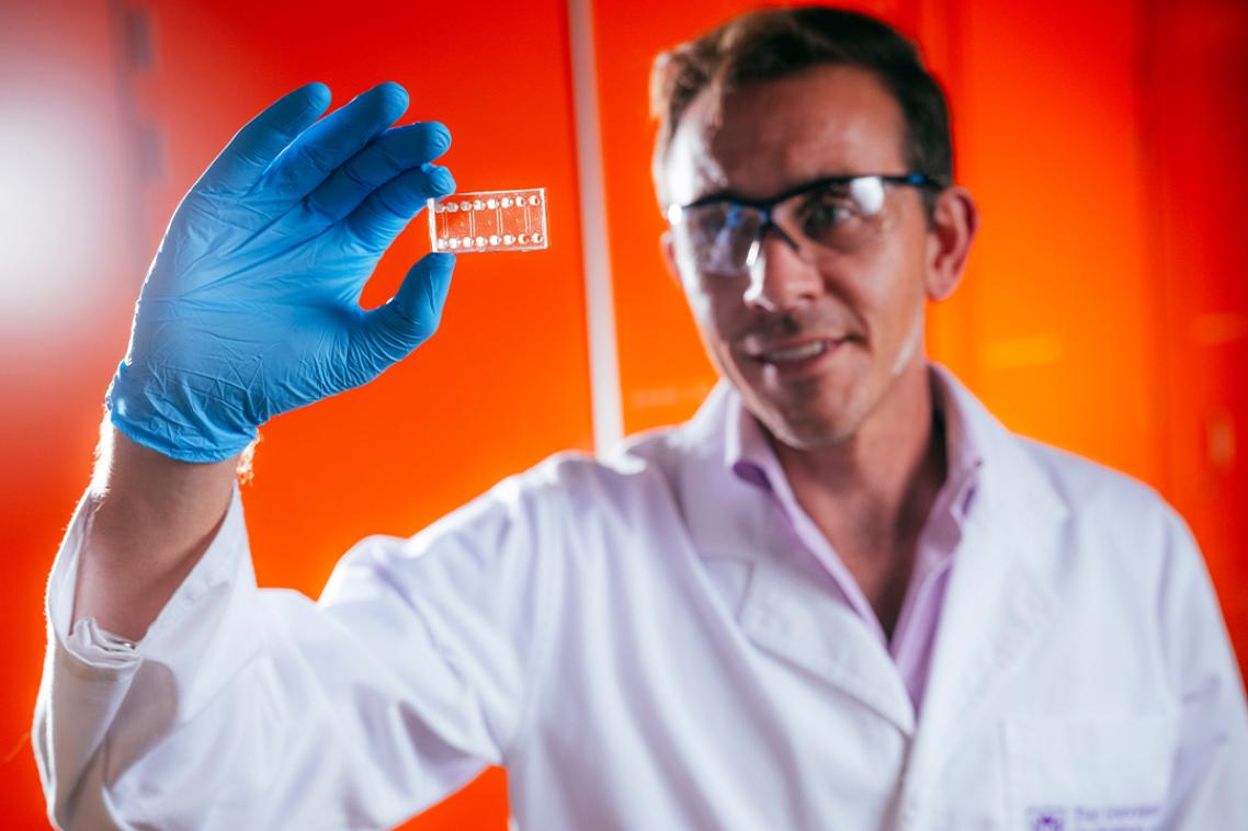 A male scientist wearing a lab coat and safety glasses.