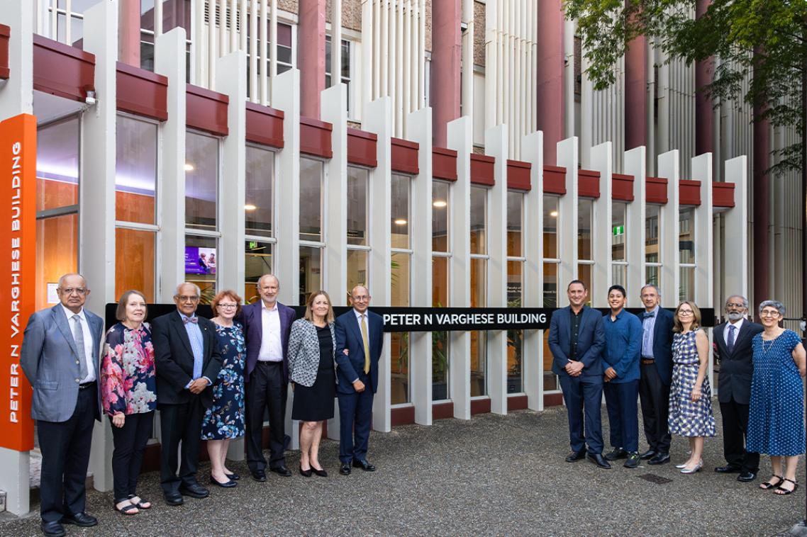 Thirteen members of the Varghese family stand in front of the Social Sciences building at The University of Queensland with new signage announcing it as the Peter N Varghese Building.